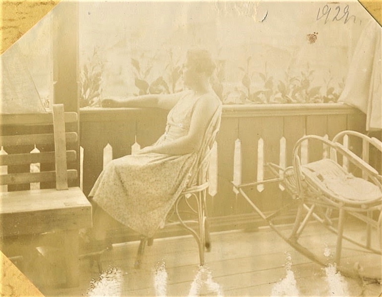 1928 год. «Это наш балкон во весь торец дома, стёкол не было, стен не было, только деревянное ограждение, стояли лавочка и кресло-качалка, висели полотняные большие занавески, которые могли закрываться на ночь или от солнца загораживать. Вот так жили — ничего не боялись». Евгения Васильевна Иванова на террасе только что построенного дома, 1928 год.